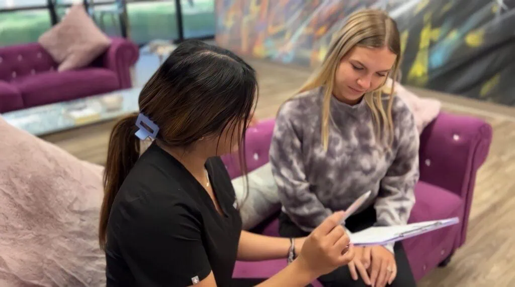 Patient consultation in orthodontic office, discussing braces and clear aligners, comfortable setting with purple furniture.