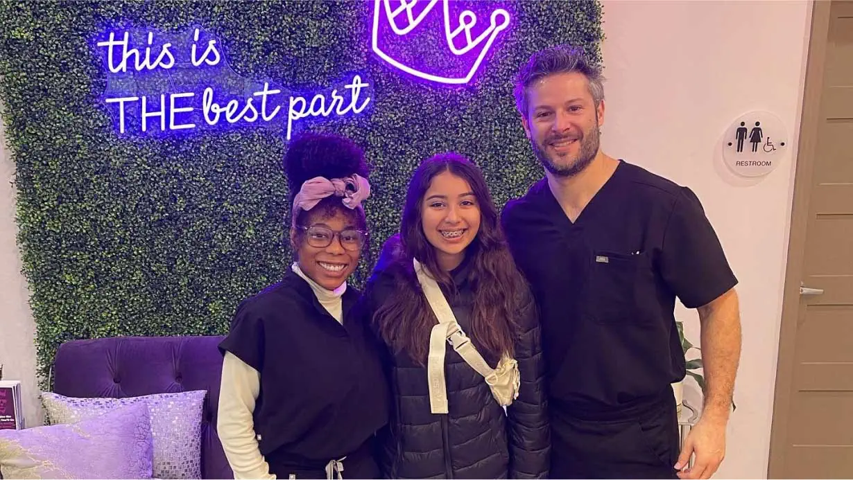 Teen patient with braces smiling with Imagine Orthodontic Studio team members in Tampa, FL