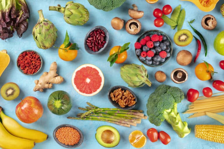 Vegan food. Healthy diet concept. Fruits, vegetables, pasta, nuts, legumes, mushrooms, shot from above on a blue background. A flat lay composition