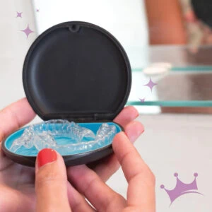 Clear aligners in a black case with a blue interior, held by a hand, emphasizing orthodontic treatment options like Invisalign for correcting dental issues.