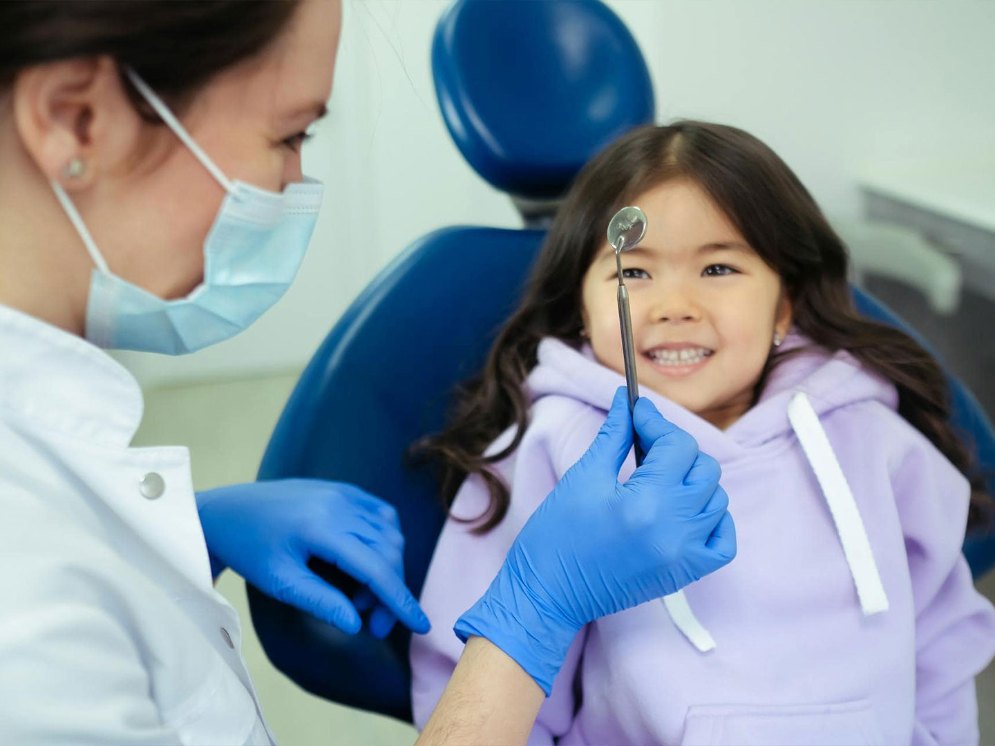 Orthodontist examining a smiling young girl during a visit at Imagine Orthodontic Studio